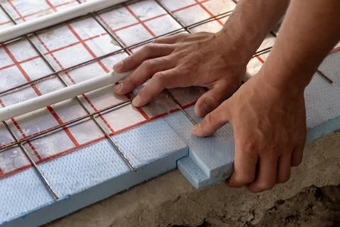 Closeup of contractor hands fixing underfloor heating pipes to foam insulat.. Stock Photos