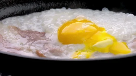Closeup of Cooking Bacon and Egg in frying Pan. Fast and easy breakfast concept. 스톡 동영상 334643392