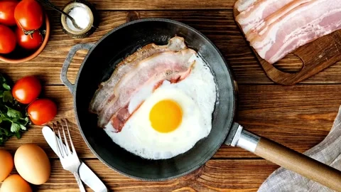 Closeup of Cooking Bacon and Egg in frying Pan. Fast and easy breakfast concept. 스톡 동영상 334643401