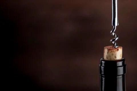 A closeup of a corkscrew pulling a cork from a bottle of wine on a dark 写真素材