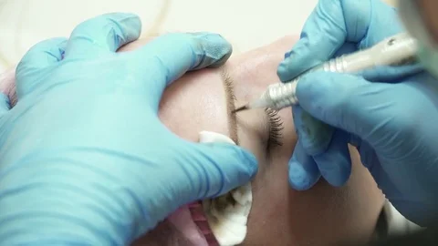 Closeup of cosmetologist is making an eyebrow permanent makeup in salon closeup Stock Footage 74215707