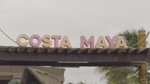 Closeup of Costa Maya sign beneath an overcast sky, with palm trees swaying in Stock Footage 309001979