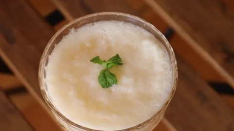 Closeup of creamy melon cocktail with mint leaf served in glass on wooden Stock Footage 313794037