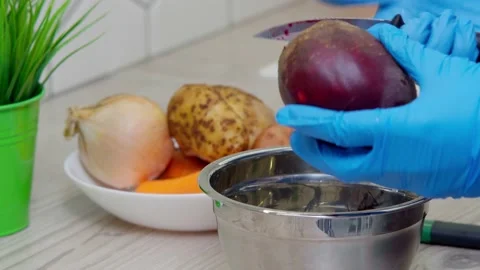 Closeup cropped hand in blue gloves peeling beetroot fast with special blade Stock Footage 232432146