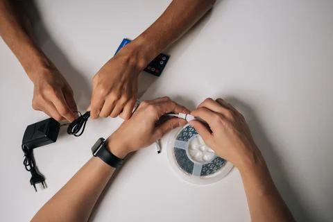 Closeup cropped shot of two technicians connecting RGB led strip lights Stock Photos