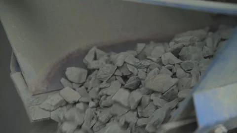 Closeup of crushed stone is dumped from a conveyor onto a moving belt. Видео 145410995