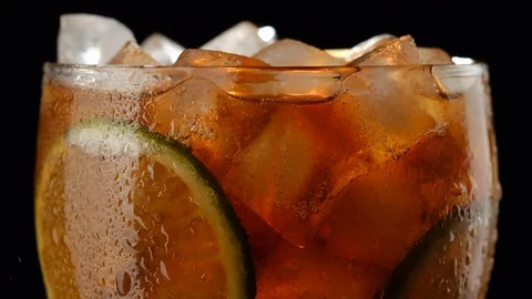 Closeup Cuba libre cocktail or Cola drink with Ice cubes, bubbles, lime Видео 121875791