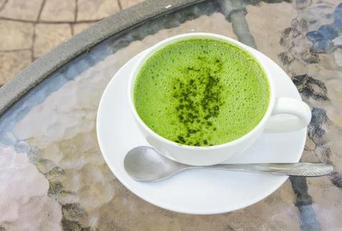 Closeup a cup of matcha latte or green tea on glass table background Stock Photos