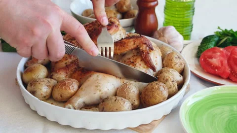 Closeup of a cut piece of fried chicken served with young potatoes, festive Stock Footage 107979822