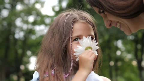 Closeup of cute 5 years old girl sniffing chamomile with mom, having a nice time Stock Footage 221271789