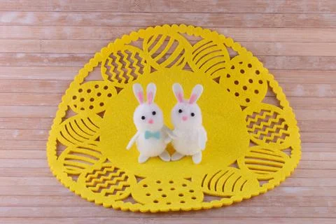 Closeup of cute Easter bunny couple hugging on yellow Easter egg lace doily on w Stock Photos