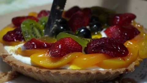 Closeup cutting with hands and a knife a fruit tart with strawberries, grapes, Vidéo 167049797
