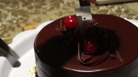 Closeup cutting with a knife a chocolate cake with cherries on a table for a Video stock 167293709