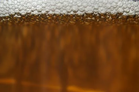 A closeup of dark beer in a cup with bubble suds at the top Stock Photos