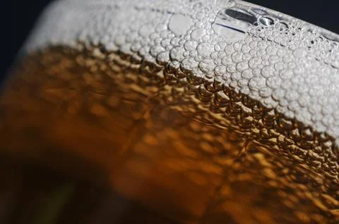 A closeup of dark beer in a cup with bubble suds at the top Stock Photos