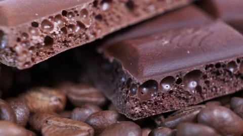 Closeup of dark roasted coffee beans and chocolate on rotating table. Video stock 140090120