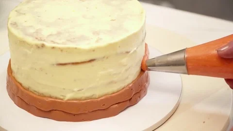 Closeup of decarating a cake with a cream while spinning Stock Footage 74586932