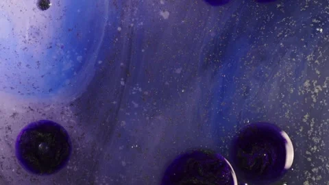 Closeup of deep violet and blue ink drops swirling and expanding in liquid. Bubb Stock Footage 311540419