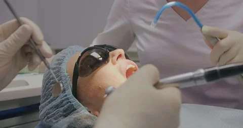 Closeup of dentists in white uniform treating teeth to young woman patient with Stock Footage 108542025