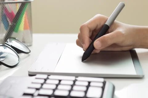 Closeup designer hand using graphic tablet on desk Stock Photos