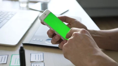 Closeup of designer using smartphone at desk with blank chroma key display Stock Footage 72870121