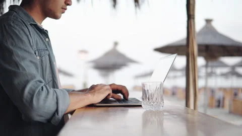 Closeup of devloper man hands typing, coding on a laptop while on in a beach  Stock Footage 237168068