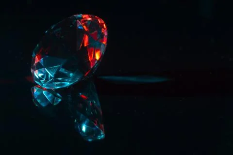 Closeup of a diamond on a black mirror surface with red and blue highlights Stock Photos