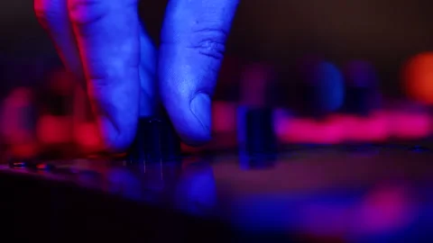 Closeup of DJs hands twisting knobs on mixing console adjusting volume of music 스톡 동영상 187045009