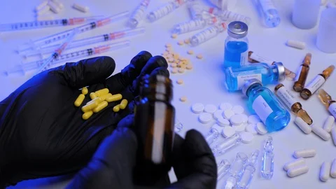 Closeup of doctor's hand in black gloves taking yellow pills from bottle Stock Footage 129707105