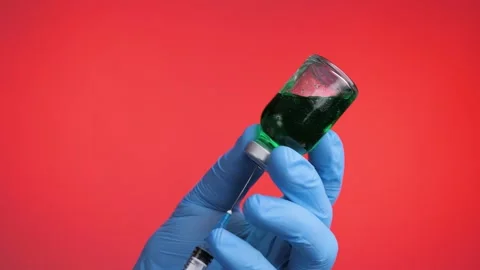 Closeup of doctor's hand in blue gloves fill syringe on a red background. Stock Footage 130902704