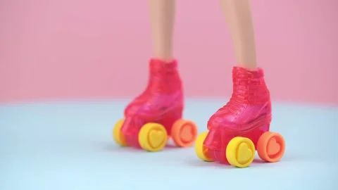 Closeup doll legs in bright roller skates. rotation on pink and blue background. Stock Footage 303465112