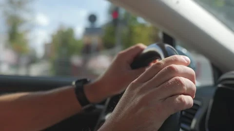 Closeup of driver keeping both hands on steering wheel as car moves along road Stock Footage 346653894