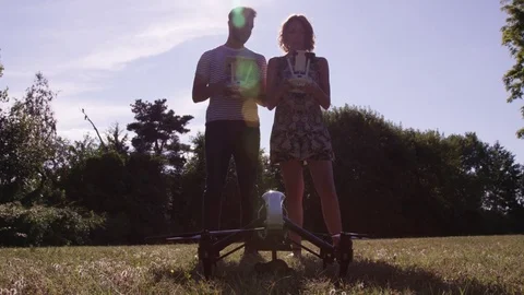 Closeup Drone Taking Off With Man and Woman Pilots With Remote Controlls In Slow Stock Footage 82582408