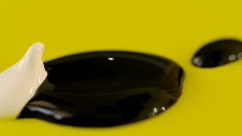 Closeup of a drop of white and brown paint on a yellow background Stock Footage 101454730