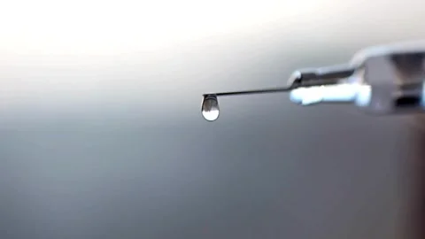 Closeup droplets of clear liquid fall and spurt from syringe medication medical Stock-Footage 336587331