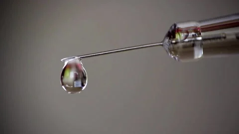 Closeup droplets of clear liquid fall and spurt from syringe medication medical Stock-Footage 336587366
