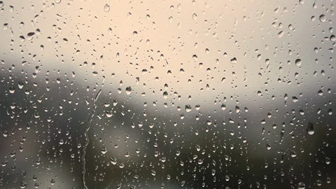 Closeup droplets of rain running down glass window on cloudy day Stock Footage