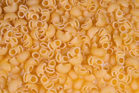 Closeup of dry pasta shells. Detailed shot of golden dry pasta shells with ridge 스톡 사진