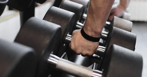 Closeup of dumbbells row. Man hands take dumbbells from gym stand. Stock Footage 158760404