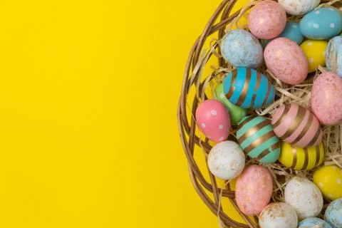 Closeup of Easter eggs in basket on yellow background. Top view of festive eg Stock-Fotos