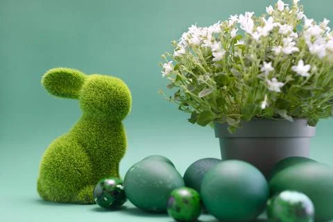 Closeup Easter green bunny, rabbit with blue colored chicken quail eggs on blue Foto stock