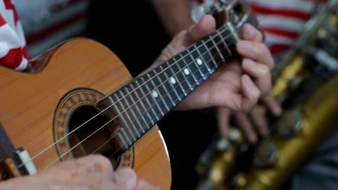 Closeup of an elderly man playing ukelele in a band in a flea market Stock Footage 140066137