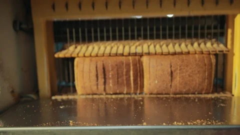 Closeup of electric slicing machine automatically cutting bread into pieces. 库存影片 120553241