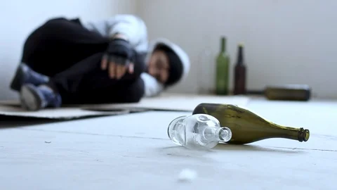 Closeup empty glass bottles. On background young homeless drunk man is sleepi Stock Footage 128646765