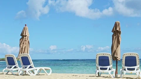 Closeup empty golden sand seashore with long beach chairs and closed umbrellas Stock Footage 129772773