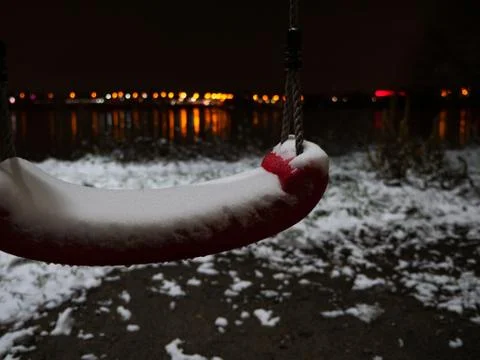 Closeup of empty swing covered by ice at winter night. Stock Photos