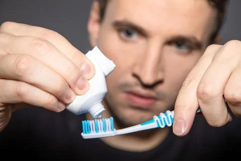 Closeup of empty tube of toothpaste with man in background squeezing the Stock Photos