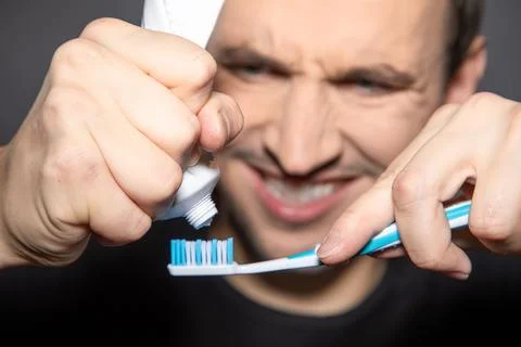 Closeup of empty tube of toothpaste with man in background squeezing the Stock Photos