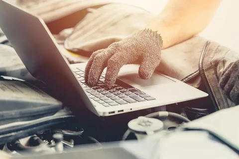 Closeup engineer service professional using laptop computer tuning car engine 写真素材