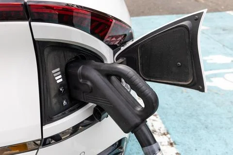 Closeup of EV car plugged in with fast charger at charging station. Stock Photos